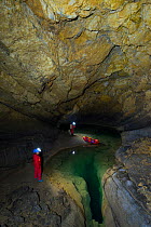 People exploring underground lakes in via rigid inflatable boat, Cross Cave (Krizna jama) under Cross Mountain, Green Karst, Slovenia, October 2014.