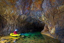 Man exploring underground lakes via rigid inflatable boat, Cross Cave (Krizna jama) under Cross Mountain, Green Karst, Slovenia, October 2014.
