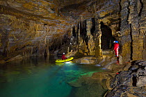 People exploring underground lakes via rigid inflatable boat, Cross Cave (Krizna jama) under Cross Mountain, Green Karst, Slovenia, October 2014.