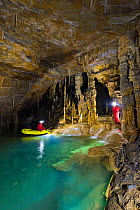 People exploring underground lakes via rigid inflatable boat, Cross Cave (Krizna jama) under Cross Mountain, Green Karst, Slovenia, October 2014.