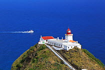 Goncalo Velho lighthouse, with motor boat driving past, Ponta do Castelo, Eastern Santa Maria Island, Azores, Portugal, Atlantic Ocean. August 2014.