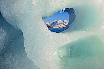 View through glacier ice towards snow-covered mountains in Kongsfjorden fjord in Svalbard, Spitsbergen, Norway.