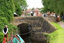 Sue Day, in a Victorian dress, towing, with her draft horse, Maria, a 1814 wooden narrowboat, on the canals, near Marple, Metropolitan Borough of Stockport, Greater Manchester, England. June 2015.