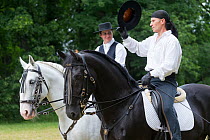 Two riders, dressed in Spanish period costume, ride two rare Kladruber horses/stallions (one black, one white), at the Great Riding festival, in Slatinany national stud, Pardubice Region, Czech Republ...