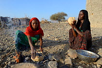Afar tribe women baking bread with a hot stone on open fire, Malab-Dei village, Danakil depression, Afar region, Ethiopia, March 2015.