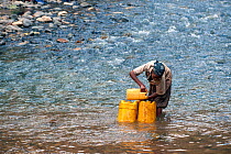 Oromo tribe girl filling her yellow water containers from the Web River (Weyib River) in Islams sacred valley - Sof Omar. Bale Province, Oromia Region, Ethiopia, Africa, March 2009