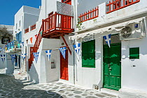 Picturesque alley in Mykonos Town with white houses, green doors and red balconies decorated with the Greek flag bunting, Mykonos Island, Cyclades, Aegean Sea, Mediterranean, Greece, August 2007.
