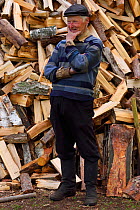 Subsistence farmer standing in front of log pile, Musteika Village, Lithuania, May 2015.