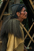 Apatani man with traditional hair knot fixed by a skewer or Piidin Khotu and traditional Lecha over shoulder and cane hat which includes a hornbills beak. Apatani Tribe, Ziro Valley, Himalayan Foothil...
