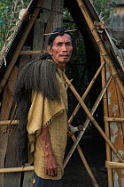 Apatani man with traditional hair knot fixed by a skewer or Piidin Khotu and traditional Lecha over shoulder and cane hat which includes a hornbills beak. Apatani Tribe, Ziro Valley, Himalayan Foothil...