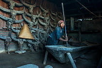 Konyak Naga woman pounding rice. Mon district. Nagaland,  North East India, October 2014.