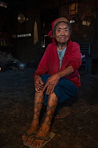 Portrait of elderly Ao Naga woman with leg tattoos. Ao Naga headhunting Tribe. Mokokchung district. Nagaland, North East India, October 2014.