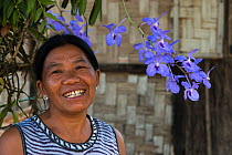 Ao Naga woman standing next to purple orchids, Mokokchung district. Nagaland, North East India, October 2014.