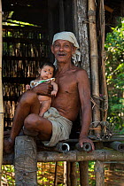 Mising man with baby, Majuli Island, Brahmaptura River, Assam, North East India, October 2014.