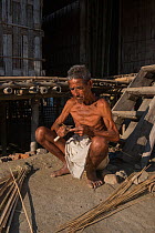 Mising Tribe man weaving baskets out of cane, Majuli Island, Brahmaputra River, Assam,  North East India. October 2014.
