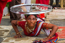 Hirja performer, balancing bicycle wheel on head, Hijra are transgender people, legally recognized as a third gender in India.  Uttar Pradesh, India, October 2014.