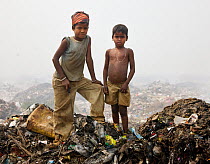 Indian rag picker boys standing on rubbish heap in landfill site, Guwahati, Assam, India, March 2009.