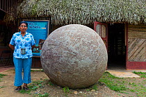 Boruca woman with stone spheres, created by the ancestors of indigenous Boruca peopla, Costa Rica. December 2014.