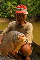 Indigenous Maijuna fisherman with Red-bellied pacu fish  (Piaractus brachypomus) Rio Napo, Loreto, Peru. October 2014.