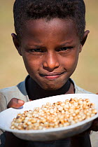Amhara child with 'kolo', a snack made from roasted barley, Jimba, Bahir Dar. Lake Tana Biosphere Reserve, Ethiopia. December 2013.