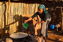 Amhara woman pouring batter made with fermented cereals to prepare traditional 'injera' bread. Jimba, Bahir Dar. Lake Tana Biosphere Reserve, Ethiopia. December 2013.