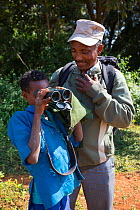 NABU employee letting child looking through binoculars at birds, Jimba, Lake Tana Biosphere Reserve, Ethiopia. December 2013.