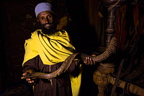 Coptic monk of Tana Qirqos Monastery, showing items in the museum. Lake Tana Biosphere Reserve, Ethiopia. December 2013.