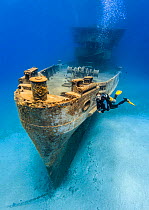 Diver  swimming alongside the bow of the USS Kittiwake (US Military submarine rescue vessel) in Grand Cayman, the Cayman Islands, Caribbean Sea. Model released