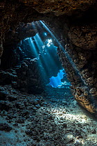 RF- Shafts of light shine through darkness of cavern within  coral reef. Sha'ab Claudia, Fury Shoal, Egypt. Red Sea. (This image may be licensed either as rights managed or royalty free.)