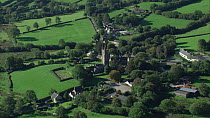 Aerial view tracking over Widecombe-in-the-Moor village church, Dartmoor National Park, Devon, England, UK, October 2015.