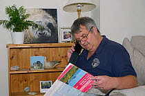 British Divers Marine Life Rescue regional co-ordinator Dave Jarvis reading report of an injured grey seal pup (Halichoerus grypus) on a Cornish beach from his home, Cornwall, UK, October.  Model rele...