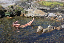Hiker soaking in thermal area of Shoshone Creek in Shoshone Geyser Basin. Yellowstone National Park, Wyoming, USA, August. Model released.