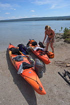 Kayaker packing gear on Shoshone Lake in Yellowstone National Park, Wyoming, USA, August 2015. Model released.