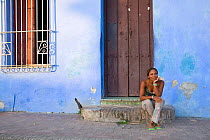 Local woman sitting in front of her house,  Camaguey, Cuba, Caribbean Sea, Atlantic Ocean. November 2007.