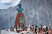 Chinstrap penguins (Pygoscelis antarcticus) with chicks by the memorial sculpture bust of Captain Luis Alberto Pardo, Elephant Island, South Shetland Islands, South Atlantic, January.