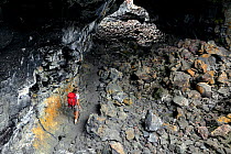 Hiker walking through Indian Tunnel in Craters Of The Moon National Monument, Idaho, USA, July 2015. Model released.