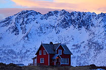 House with snowy mountains behind, Hamn i Senja, Troms County, Norway, Scandinavia, January 2015.
