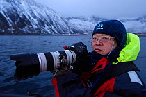 Whale watcher with camera, near Senja, Troms County, Norway, Scandinavia, January 2015. Cetaceans are attracted to this area to feed on the huge population of spring spawning Herring