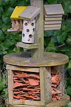 Insect hotel with a variety of crevices among broken pottery, drilled logs and wooden blocks, Gloucestershire, UK, April.