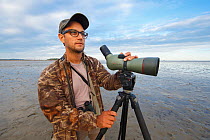 Birder looking for shorebirds on mudflats,  South Korea. October 2013.