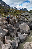 Woman photographing the Sarvesjakka river in a deep canyon, Sarvesvagge Valley, Sarek National Park, World Heritage Laponia, Swedish Lapland, Sweden, August 2013.