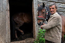 Man with horse outside a stable, Ciuc Mountains, Transylvania, Romania, May 2015.