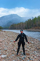Photographer Olga Kamenskaya wearing wet suit standing next to Temnik River, Lake Baikal, Baikalsky Reserve, Siberia, Russia. May 2015