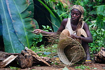 Baka woman weaving a basket from plant fibers, South East Cameroon, July 2008.