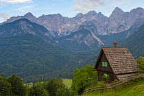 Traditional wooden house and Peaks above Gozd Martuljek including Spik (2472 m) on the right. Julian Alps, Slovenia. July 2015