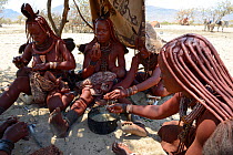 Himba women eating, Marienfluss Valley, Kaokoland Desert, Namibia. October 2015