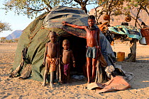 Himba children, a girl and two boys, in front of their hut, Marienfluss Valley, Kaokoland Desert, Namibia. October 2015