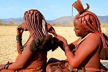 Himba women braiding each other's hair. Marienfluss Valley. Kaokoland, Namibia October 2015
