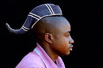 Young Himba man with single plait covered with a hat and indicating that he is unmarried. Kaokoland, Namibia October 2015