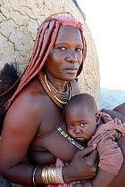 Himba woman with the typical ornaments and her baby. Kaokoland, Namibia October 2015
